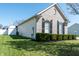 Side view of a brick home with dark shutters, green grass, and an attached shed in the backyard at 122 Stamford Dr, Pittsboro, IN 46167
