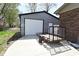 A detached garage with a white door sits on a concrete pad adjacent to the home and a small trailer at 1229 Dallas Dr, Plainfield, IN 46168