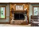 Detailed view of the fireplace with brick surround, decorative mantle, and flanking windows, adding warmth and character at 12613 Carrington Pl, Carmel, IN 46033
