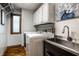Functional laundry room with modern washer and dryer, utility sink, white cabinets, and wood floors at 12613 Carrington Pl, Carmel, IN 46033