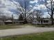 A wide view of the white home from the street, surrounded by lawns and mature trees at 130 Hiawatha Dr, Noblesville, IN 46062