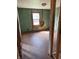 Green-painted room undergoing renovations, displaying exposed beams and a rustic window view, ripe for transformation at 130 Hiawatha Dr, Noblesville, IN 46062
