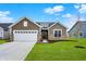 Charming single-story home features a two-car garage, stone accents, and a well-manicured lawn, blending comfort with curb appeal at 19123 River Jordan Pass, Westfield, IN 46074