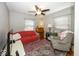 Cozy bedroom with a red sofa, patterned chair, and a ceiling fan at 19702 Tomlinson Rd, Westfield, IN 46074