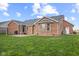 Exterior view of the red brick house, highlighting a stone patio and lush green backyard at 2511 Countryside Westview Dr, Shelbyville, IN 46176