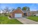 Exterior view of a red brick home featuring an attached two-car garage and green front lawn at 2511 Countryside Westview Dr, Shelbyville, IN 46176