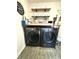 Modern laundry room with front load washer, dryer, wooden shelves, decor, and cleaning supplies at 2936 W Calimanco Ln, Monrovia, IN 46157