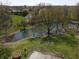 Aerial view of a picturesque property with a pond surrounded by lush greenery and mature trees at 3311 Stella St, Greenwood, IN 46143