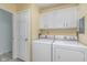 Laundry room features white cabinets and side by side washer and dryer at 3462 Briar Creek Ln, Carmel, IN 46033