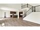 Open-concept living room boasts wood floors, staircase, and kitchen with stainless steel appliances at 3727 Thomas Jefferson Ct, Westfield, IN 46074