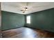 A bedroom with wood floors, a ceiling fan, green walls, and a window at 3991 Clubhouse Dr, Greenfield, IN 46140