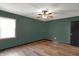 A simple bedroom features wood floors, green walls, a ceiling fan, and a window at 3991 Clubhouse Dr, Greenfield, IN 46140