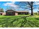 Ranch home with brick facade, green lawn, and mature tree casting shadows in a bright exterior shot at 3991 Clubhouse Dr, Greenfield, IN 46140