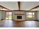 Open living room with wood floors, exposed wood beams, a brick fireplace, and sliding doors to the back yard at 3991 Clubhouse Dr, Greenfield, IN 46140