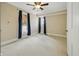 Simple bedroom with neutral walls, carpet, a ceiling fan, and multiple windows with dark blue curtains at 40 N Ritter Ave, Indianapolis, IN 46219