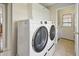 A laundry room with modern washer and dryer units, white cabinets, and neutral tile floors at 40 N Ritter Ave, Indianapolis, IN 46219
