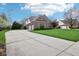 Long driveway leading to a brick home with a three-car garage, basketball hoop, and well-manicured lawn at 4281 Honeysuckle Ln, Zionsville, IN 46077