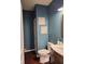 Powder room featuring blue accent walls, wood floors, and decorative wall art at 4383 Round Lake Bnd, Indianapolis, IN 46234