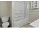 Clean, white bathroom features a tub with shower, toilet, and updated vanity with cabinet at 443 N Alton Ave, Indianapolis, IN 46222