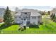 The backyard of this gray brick home features a deck, stairs to the lawn, manicured landscaping, and ample privacy at 476 Sapphire Dr, Carmel, IN 46032