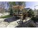 Outdoor dining area with wooden chairs and table set on a stone patio with umbrella, backyard at 537 Weyworth Pl, Greenwood, IN 46142