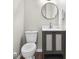 A half bathroom includes a gray vanity, a round mirror, wood-look flooring, and a white commode at 5455 S 800 E, Zionsville, IN 46077