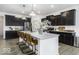 Modern kitchen boasts dark cabinets, a large island with seating, stainless steel appliances, and stylish pendant lighting at 561 Riviera Pl, Greenwood, IN 46143