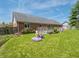 Spacious backyard showing a lawn, colorful flower bed, and brick house with a wooden deck at 575 Crestpoint Ln, Plainfield, IN 46168