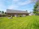 Large backyard with a green lawn, brick house, and wooden deck, surrounded by mature trees and landscaping at 575 Crestpoint Ln, Plainfield, IN 46168