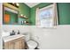 Fresh bathroom with green walls, white tile, decorative shelves, and a modern sink at 5831 Bar Del W Dr, Indianapolis, IN 46221
