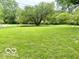 Large front yard featuring a well-maintained lawn and mature trees, offering a peaceful setting at 5846 Bellsville Pike, Columbus, IN 47201
