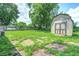 This backyard shows a green space, shed, trees, and a patio with a partial fence at 6189 Vigo Dr, Clayton, IN 46118