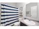 Bathroom with shower-tub combo featuring a blue striped shower curtain, plus neutral walls and flooring at 6323 Emerald Field Way, Indianapolis, IN 46221