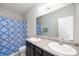 Bathroom with dual sinks, a shower-tub combo featuring a blue patterned shower curtain, plus neutral walls and flooring at 6323 Emerald Field Way, Indianapolis, IN 46221