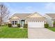 Charming brick home with a well-maintained lawn and two-car garage in a suburban neighborhood at 6323 Emerald Field Way, Indianapolis, IN 46221