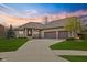 Beautiful brick home featuring a three-car garage, manicured lawn, and gorgeous landscaping at sunset at 6841 W Glory Maple Dr, McCordsville, IN 46055