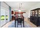Open dining area features sliding glass doors, modern light fixture, and flows into a kitchen with cherry cabinets at 7354 Ponderosa Pines Ln, Indianapolis, IN 46239