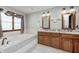 Beautiful bathroom with dual sinks, marble countertops, wood cabinets, and a tub with tile surround at 7688 Gunsmith Ct, Plainfield, IN 46168