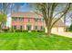 Traditional two-story brick home with an attached two-car garage, green shutters, and manicured landscaping at 7688 Gunsmith Ct, Plainfield, IN 46168
