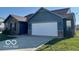 Blue home featuring a spacious driveway, two-car garage and attractive brick accents at 8019 Gathering Ln, Indianapolis, IN 46259