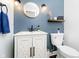 Stylish powder room with a modern vanity, round mirror, and blue accent wall at 9270 N Temple Ave, Indianapolis, IN 46240