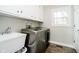 Bright laundry room with modern washer and dryer, utility sink, and storage cabinets at 9270 N Temple Ave, Indianapolis, IN 46240
