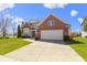 A two-story brick home featuring a two-car garage and a manicured front lawn with blue sky at 10471 Meadow Lake Dr, Fishers, IN 46038