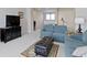 Cozy living room with blue sofa, black TV stand, and tufted ottoman on a patterned rug at 10471 Meadow Lake Dr, Fishers, IN 46038