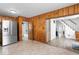 Living room with stainless steel fridge, wood paneling, and an open staircase to the upper level at 1126 N Anderson St, Elwood, IN 46036