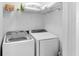A bright laundry room with white appliances and storage shelves for household supplies at 12258 Weathered Edge Dr, Fishers, IN 46037