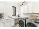 Well-organized laundry room with modern washer and dryer, sink, storage cabinets, and a decorative stained glass window at 1501 Chanson Ln, Westfield, IN 46074
