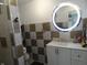 Modern bathroom with checkerboard tile, round lighted mirror, and under sink storage at 1722 N Parker Ave, Indianapolis, IN 46218