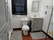 Bathroom with a toilet, modern vanity, storage and gray mats, window with dark curtain at 1722 N Parker Ave, Indianapolis, IN 46218