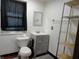 Bathroom with a modern vanity, toilet, and metal storage rack; includes window with dark curtain at 1722 N Parker Ave, Indianapolis, IN 46218